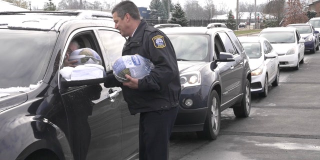 A Jackson police officer hands out a turkey to a local resident as a part of the city's first ever turkey giveaway.