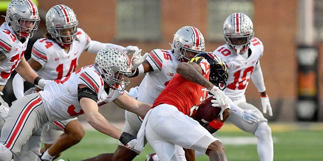 Ohio State defensive end Jack Sawyer (33), safety Ronnie Hickman (14), linebacker Tommy Eichenberg (35), safety Tanner McCalister (15) and cornerback Denzel Burke (10) converge on Maryland wide receiver Jacob Copeland (2) during a game November 19, 2022, at Capital One Field at Maryland Stadium in College Park, Maryland.