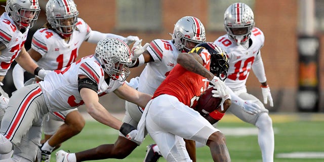 Ohio State defensive end Jack Sawyer (33), safety Ronnie Hickman (14), linebacker Tommy Eichenberg (35), safety Tanner McCalister (15) and cornerback Denzel Burke (10) converge on Maryland wide receiver Jacob Copeland (2) during a game Nov. 19, 2022, at Capital One Field at Maryland Stadium in College Park, Md.