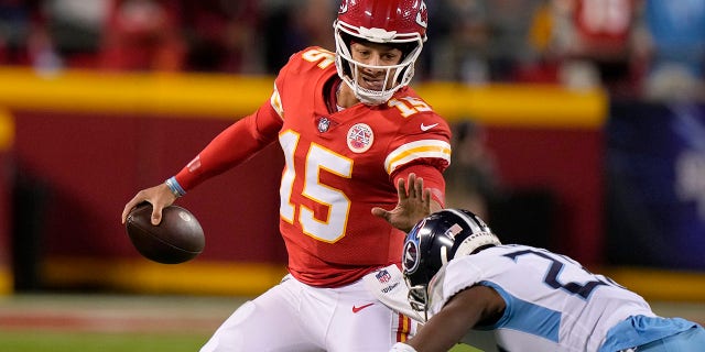 Kansas City Chiefs quarterback Patrick Mahomes (15) scrambles past Tennessee Titans safety Joshua Kalu during the first half of an NFL football game Sunday, Nov. 6, 2022, in Kansas City, Mo.
