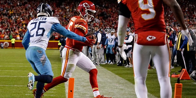 Kansas City Chiefs quarterback Patrick Mahomes (15) scores a 2-point conversion past Tennessee Titans cornerback Kristian Fulton (26) as Chiefs' wide receiver JuJu Smith-Schuster (9) watches during the second half of an NFL football game Sunday, Nov. 6, 2022, in Kansas City, Mo. 