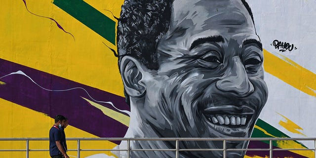 A man walks past a mural painting depicting legendary Brazilian footballer Pele near the Khalifa International Stadium in Doha on November 18, 2022, ahead of the Qatar 2022 World Cup football tournament.