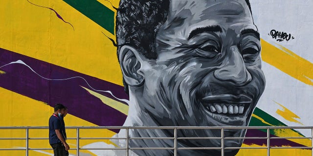 A man walks past a mural painting depicting legendary Brazilian footballer Pele near the Khalifa International Stadium in Doha on November 18, 2022, ahead of the Qatar 2022 World Cup football tournament.
