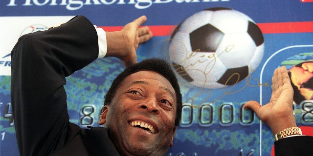 El gran jugador de fútbol Pelé hace un gesto para lanzar una pelota de fútbol de cartón durante una conferencia de prensa promocional para la nueva tarjeta Visa de la Copa Mundial del Banco de Hong Kong, Hong Kong el 24 de febrero.  Es probable que Brasil presente una candidatura para albergar la Copa del Mundo de 2006 contra países como Alemania, Inglaterra y Sudáfrica, según la leyenda del deporte brasileño, que se encuentra en Hong Kong por negocios y para asistir a una escuela de entrenadores.