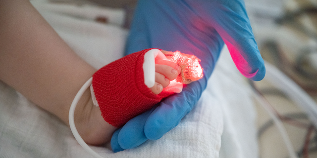 An intensive care nurse holds the foot of a patient suffering from respiratory syncytial virus (RSV), who is being ventilated, in the pediatric intensive care unit of the Olgahospital of the Klinkum Stuttgart.