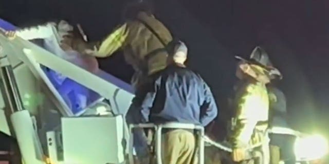 One of the teenage girls trapped on a roller coaster in North Highlands, California, makes her way down an aerial ladder.