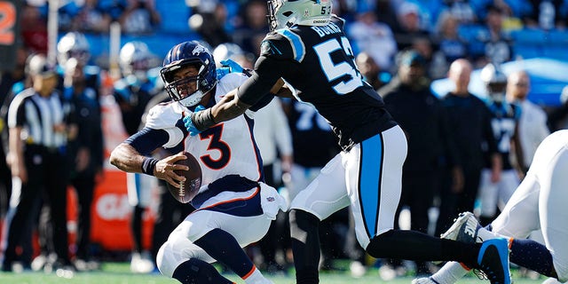 Denver Broncos quarterback Russell Wilson slides under pressure by Panthers defensive end Brian Burns Sunday, Nov. 27, 2022, in Charlotte, North Carolina.