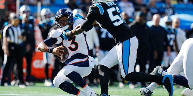 Denver Broncos quarterback Russell Wilson slides under pressure by Panthers defensive end Brian Burns Sunday, Nov. 27, 2022, in Charlotte, North Carolina.