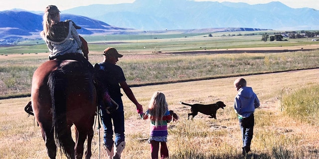Shane Adams leads his horse Mongo as family members accompany him. One of his nieces is riding Mongo in this image, with son Owen tucked right in front of her. 
