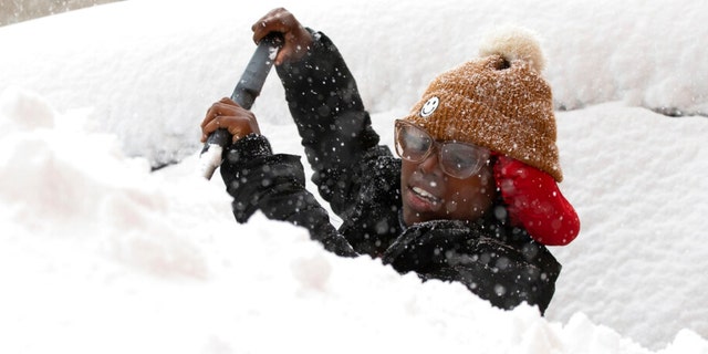 Zaria Black, 24, from Buffalo, clears off her car as snow falls Friday, Nov. 18, 2022, in Buffalo, N.Y.  A dangerous lake-effect snowstorm paralyzed parts of western and northern New York, with nearly 2 feet of snow already on the ground in some places and possibly much more on the way.  