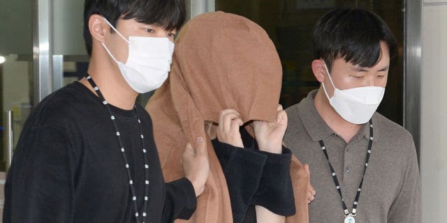 A woman, center, leaves to the Seoul Central District Prosecutors' Office at Ulsan Jungbu police station in Ulsan, South Korea, on Sept. 15, 2022. A South Korean court has approved the extradition of the 42-year-old woman facing murder charges in New Zealand over her possible connection to the bodies of two long-dead children found abandoned in suitcases in August.
