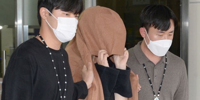 A woman, center, leaves to the Seoul Central District Prosecutors' Office at Ulsan Jungbu police station in Ulsan, South Korea, on Sept. 15, 2022. A South Korean court has approved the extradition of the 42-year-old woman facing murder charges in New Zealand over her possible connection to the bodies of two long-dead children found abandoned in suitcases in August.
