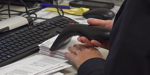 An elections office employee scans mail-in ballots in Lebanon, PA. 