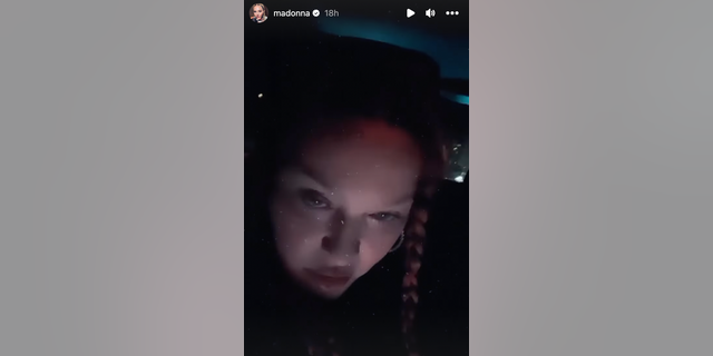 Madonna is seen staring into the camera in a close up shot while in a dark car.