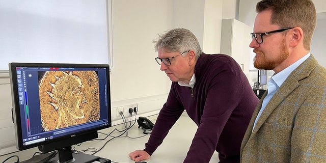 Os professores Paul N. Pearson e Jesper Ericsson, The Hunterian, da Universidade de Glasgow, observam a moeda Sponsiana sob um microscópio.