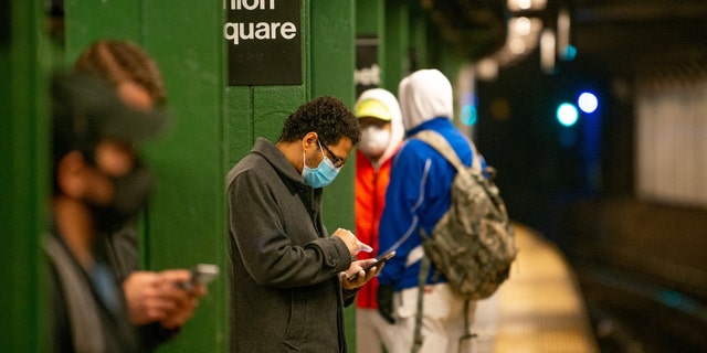 A man wearing a mask and gloves looks at his phone in the Union Square subway station on May 6, 2020, in New York City.  