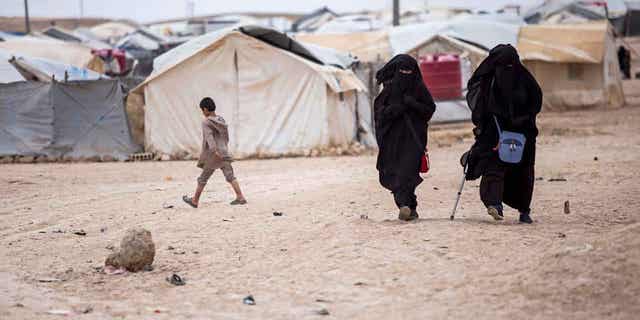 Women walk in al-Hol camp which hosts around 60,000 refugees, including families and supporters of the Islamic State group, many of them foreign nationals, in Hasakeh province, Syria, May 1, 2021. 