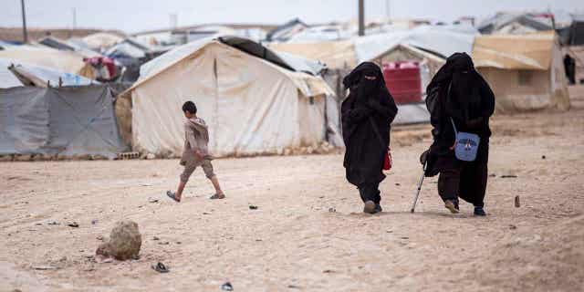 Women walk in the Al-Hol camp, which is home to about 60,000 refugees, including families and supporters of the Islamic State group.