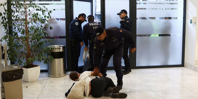 Police officers remove a protester for climate change and against the use of fossil fuels from a private event which, according to local media, Antonio Costa Silva, Portugal's Minister of Economy and Maritime Affairs was attending in Lisbon, Portugal, November 12, 2022. 