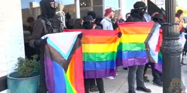 Exterior view of the bookstore with Antifa standing outside carrying lgbtq+ flags