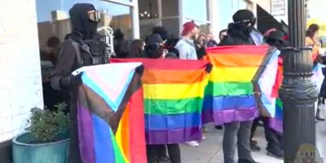 Exterior view of the bookstore with Antifa standing outside carrying lgbtq+ flags