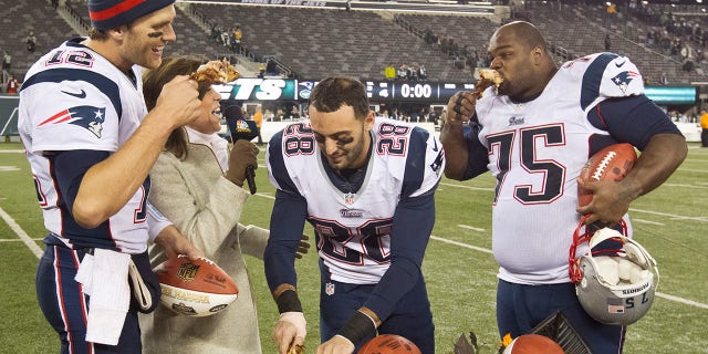 New England Patriots players, from left, Tom Brady, Steve Gregory and Vince Wilfork join television broadcaster Michele Tafoya eating turkey legs after defeating the New York Jets 49-19 during a Thanksgiving Day game at MetLife Stadium on Nov. 22, 2012.