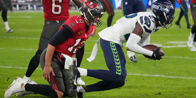 O cornerback do Seattle Seahawks, Tariq Woolen, à direita, intercepta um passe destinado ao quarterback do Tampa Bay Buccaneers, Tom Brady, à esquerda, durante o segundo tempo na Allianz Arena, em 13 de novembro de 2022, em Munique, Alemanha.