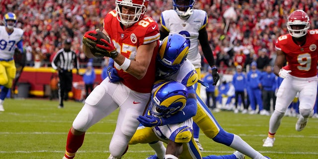 El ala cerrada de los Kansas City Chiefs, Travis Kelce (87), anota en una recepción de touchdown de 39 yardas que supera al profundo de Los Angeles Rams, Nick Scott, abajo a la derecha, y al esquinero Jalen Ramsey durante la primera mitad de un partido de fútbol americano de la NFL el domingo 27 de noviembre de 2022. en Kansas City, Missouri 