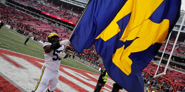 Michigan offensive lineman Trente Jones waves a team flag as he celebrates the Wolverines' victory over Ohio State on November 26, 2022, in Columbus, Ohio.