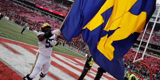 Michigan offensive lineman Trente Jones waves a team flag as he celebrates the Wolverines' victory over Ohio State on November 26, 2022, in Columbus, Ohio.