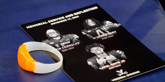 A commemorative card and light up bracelet rest on a seat before a memorial service for University of Virginia football players Lavel Davis Jr., D'Sean Perry and Devin Chandler at John Paul Jones Arena at the school in Charlottesville, Va., Saturday, Nov. 19, 2022.