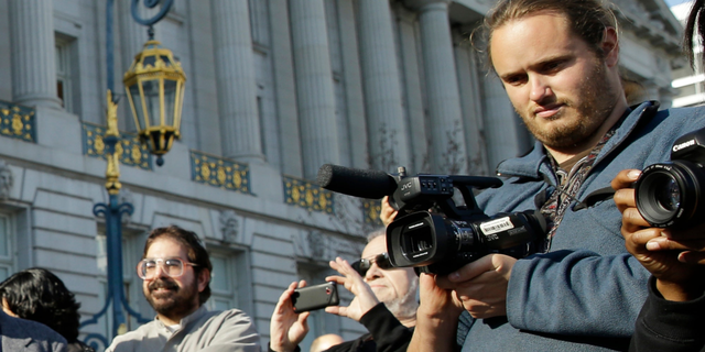 David DePape, right, records the nude wedding of Gypsy Taub outside City Hall on Dec. 19, 2013, in San Francisco. DePape is accused of breaking into House Speaker Nancy Pelosi's California home and severely beating her husband with a hammer. DePape was known in Berkeley, Calif., as a pro-nudity activist who had picketed naked at protests against local ordinances requiring people to be clothed in public.