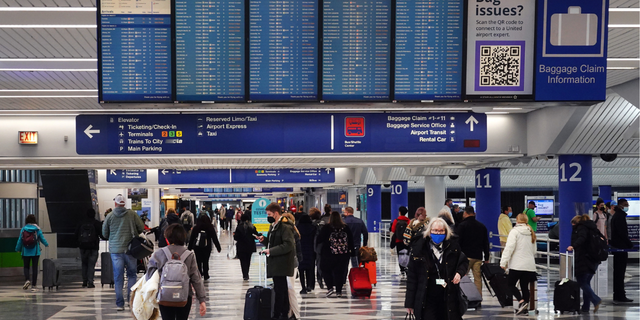 Travelers collect their luggage at baggage claim after arriving at O'Hare International Airport in Chicago on March 11, 2022.
