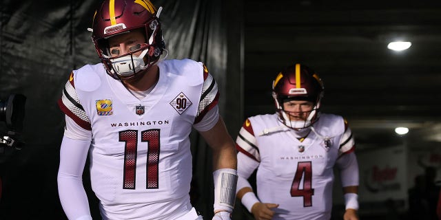 Carson Wentz, #11, and Taylor Heinicke, #4 of the Washington Commanders, jump onto the field before the game against the Chicago Bears at Soldier Field on October 13, 2022 in Chicago.