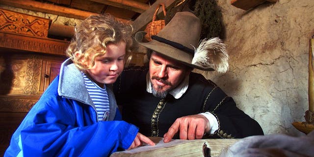 Pilgrim Edward Winslow, portrayed by Michael Hall, reads a passage from the Bible with Leah Pearl, 8, of Nantucket, as she visited his home at the Plimoth Plantation in Plymouth, Massachusetts.