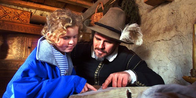 Pilgrim Edward Winslow, portrayed by Michael Hall, reads a passage from the Bible with Leah Pearl, 8, of Nantucket, as she visited his home at the Plimoth Plantation in Plymouth, Massachusetts. 