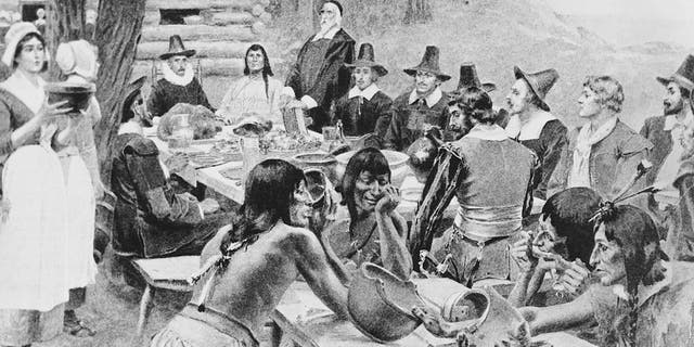 A depiction of early settlers of the Plymouth Colony sharing a harvest Thanksgiving meal with members of the local Wampanoag tribe at the Plymouth Plantation, Plymouth, Massachusetts, 1621.