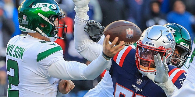New England Patriots linebacker Josh Uche, right, attempts to prevent New York Jets quarterback Zach Wilson from getting a pass attempt off. 