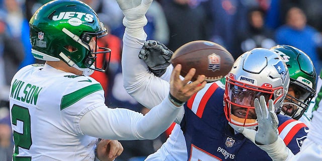 New England Patriots linebacker Josh Uche, right, attempts to prevent New York Jets quarterback Zach Wilson from getting a pass attempt off. 