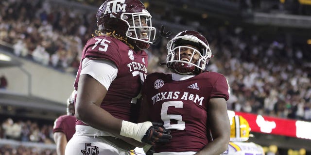 Devon Achane #6 of the Texas A&M Aggies celebrates his rushing touchdown with Kam Dewberry #75 of the Texas A&M Aggies against the LSU Tigers during the second half at Kyle Field on November 26, 2022 in College Station, Texas. 