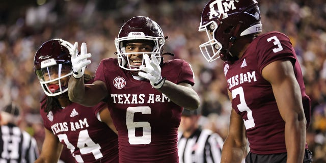 Devon Achane #6 celebrates his rushing touchdown with Devin Price #3 and Max Johnson #14 of the Texas A&M Aggies against the LSU Tigers during the second half at Kyle Field on November 26, 2022 in College Station, Texas.