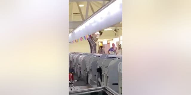 The angry customer can be seen climbing over the check-in desk and yelling at the people who tried to get him off the seat.