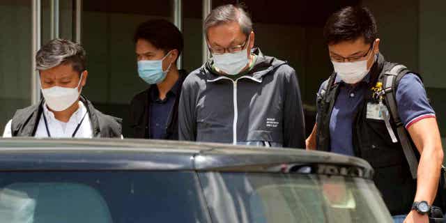 Hong Kong police officers escort Cheung Kim-hung, center, CEO and executive director of Next Digital Ltd to Apple Daily headquarters in Hong Kong. Six former Apple Daily executives pleaded guilty to one count of collusion on November 22, 2022, under the National Security Law that has jailed most of the opposition voices on Chinese soil.