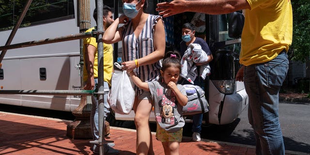 Silvia Moreno del Castillo, center, of Lima, Peru, holds her 3-year-old daughter Brisa by the hand, followed by her husband Gerardo Puente. The family seeking asylum from Peru is greeted by members of nonprofit SAMU First Response, as they leave a bus of asylum seekers who were sent from Arizona to Washington on Aug. 11, 2022.