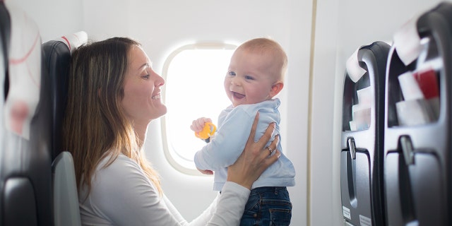 baby smiling on airplane with mother