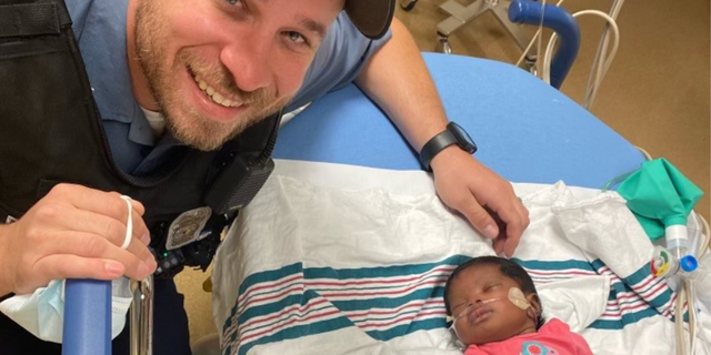 Kansas City Police officer Richard DuChaine in photo with baby he helped save. 