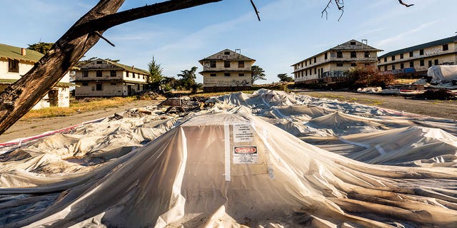 A sheet of warnings about asbestos and lead covers the rubble of the demolished barracks at Fort Ord on April 29, 2021 in California. 