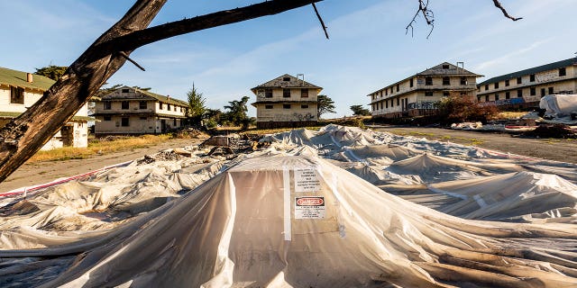 A sheet of warnings about asbestos and lead covers the rubble of the demolished barracks at Fort Ord on April 29, 2021 in California. 