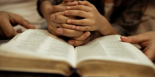 child reading Bible with adult