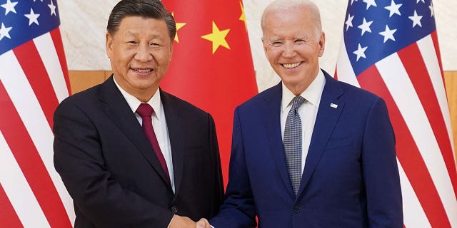 Biden and Xi shake hands in front of the Chinese and US flags